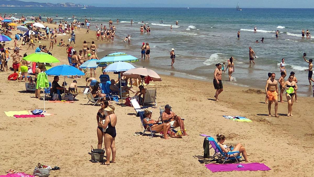 Clientes de una heladería y un coche patrulla de la Policía Nacional en el paseo marítimo, el viernes por la tarde. | PERALES IBORRA