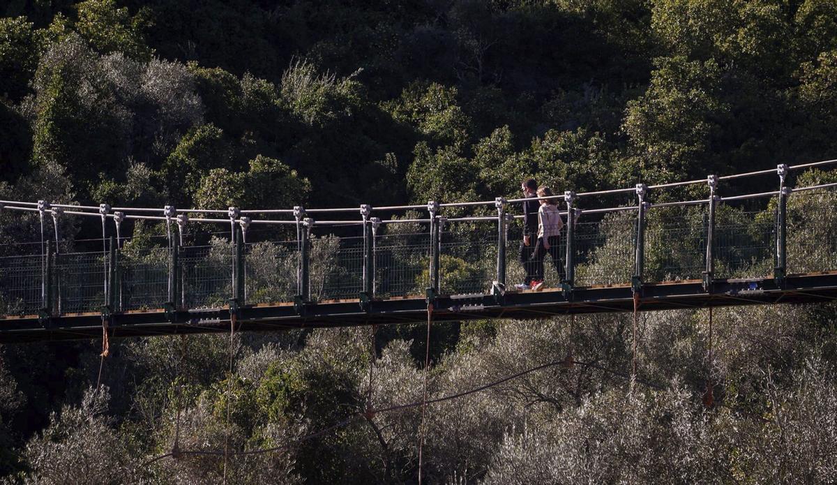 Dos mujetes pasean por uno de los puentes colgantes del Cinturón Verde de Córdoba.