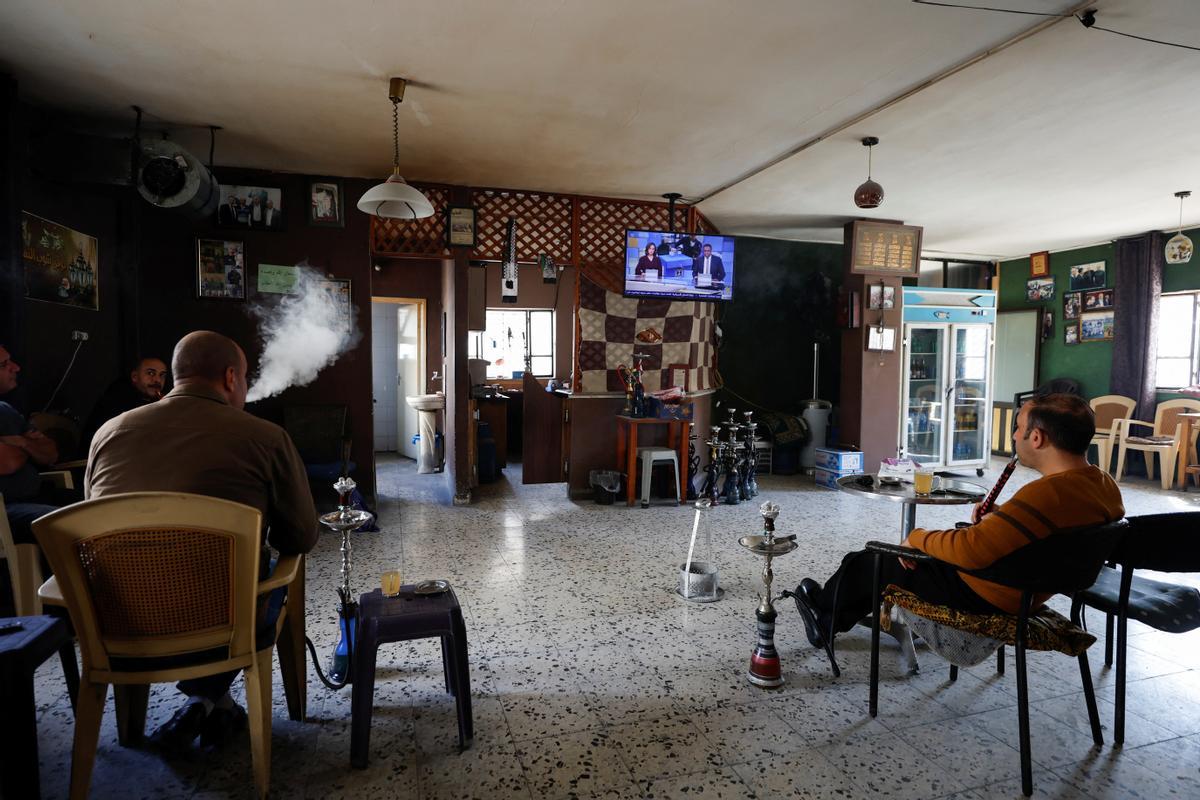 Los palestinos fuman shisha mientras ven las noticias de televisión sobre las elecciones israelíes, en Hebrón, Cisjordania ocupada por Israel.
