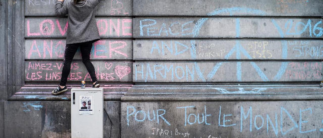 Una chica escribe un mensaje en recuerdo de las víctimas del atentado del martes pasado en un muro de la Plaza de la Bolsa de Bruselas (Bélgica), un día después de los atentados.