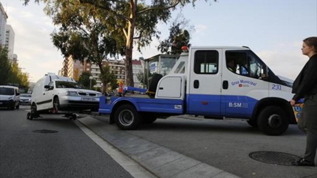 Un vehículo que había estado mal estacionado es remolcado por la grúa hacia el depósito municipal, el miércoles, en la calle de Tarragona.