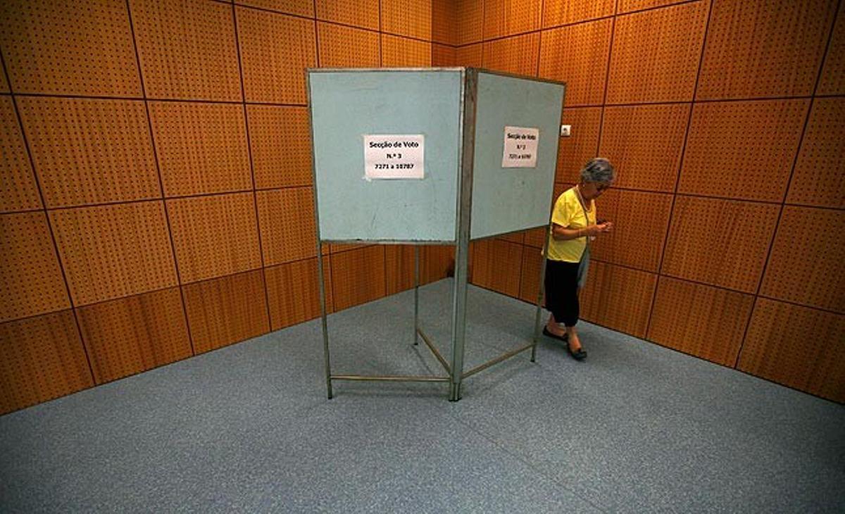 Una dona abandona un centre electoral de Lisboa després de votar en les eleccions generals de Portugal aquest diumenge. Els conservadors de Passos Coelho han aconseguit una clara victòria i hauran d’aplicar les mesures d’austeritat exigides per la UE i l’FMI després de concedir al país un préstec de 78.000 milions d’euros.