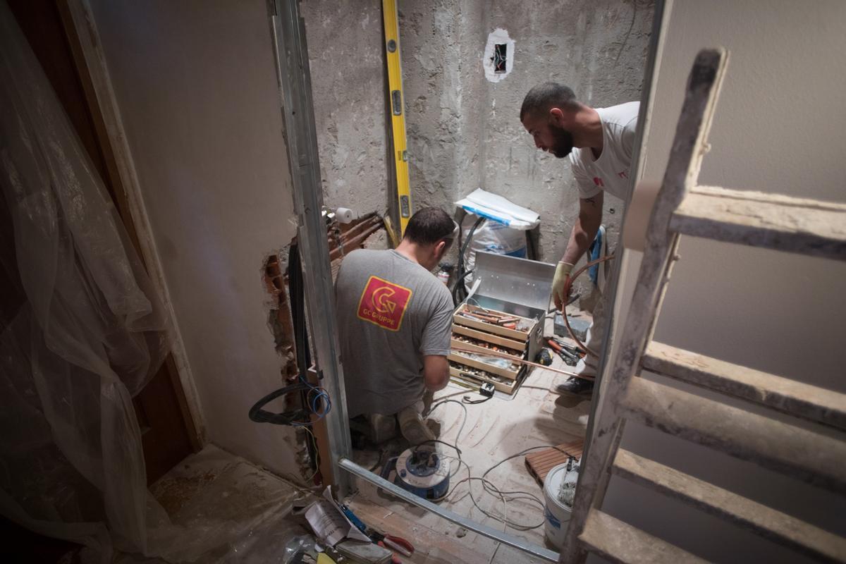 Dos albañiles realizan una reforma en un baño en una vivienda de Barcelona.