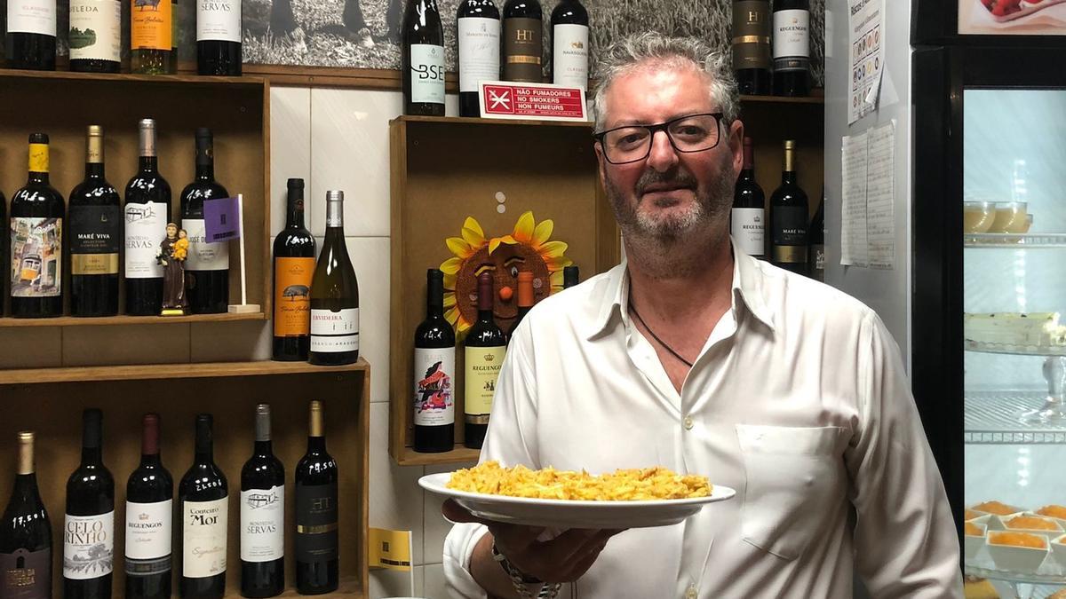 ntonio Canhoto posa en la barra de su local con un plato de bacalao a la dorada