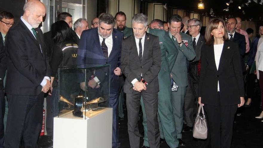 Por la izq., Féliz Azón, delegado del Gobierno en Madrid, José Manuel Rodríguez Uribes y Grande-Marlaska observan una vitrina donde se exponen restos de la carrocería de un coche de la Guardia Civil dañado por un atentado de ETA y un tricornio de una víctima. A la dcha., la secretaria de Estado Ana Botella. // Modem Press