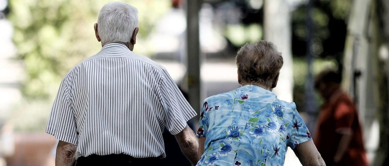 Una pareja de pensionistas paseando por un parque.