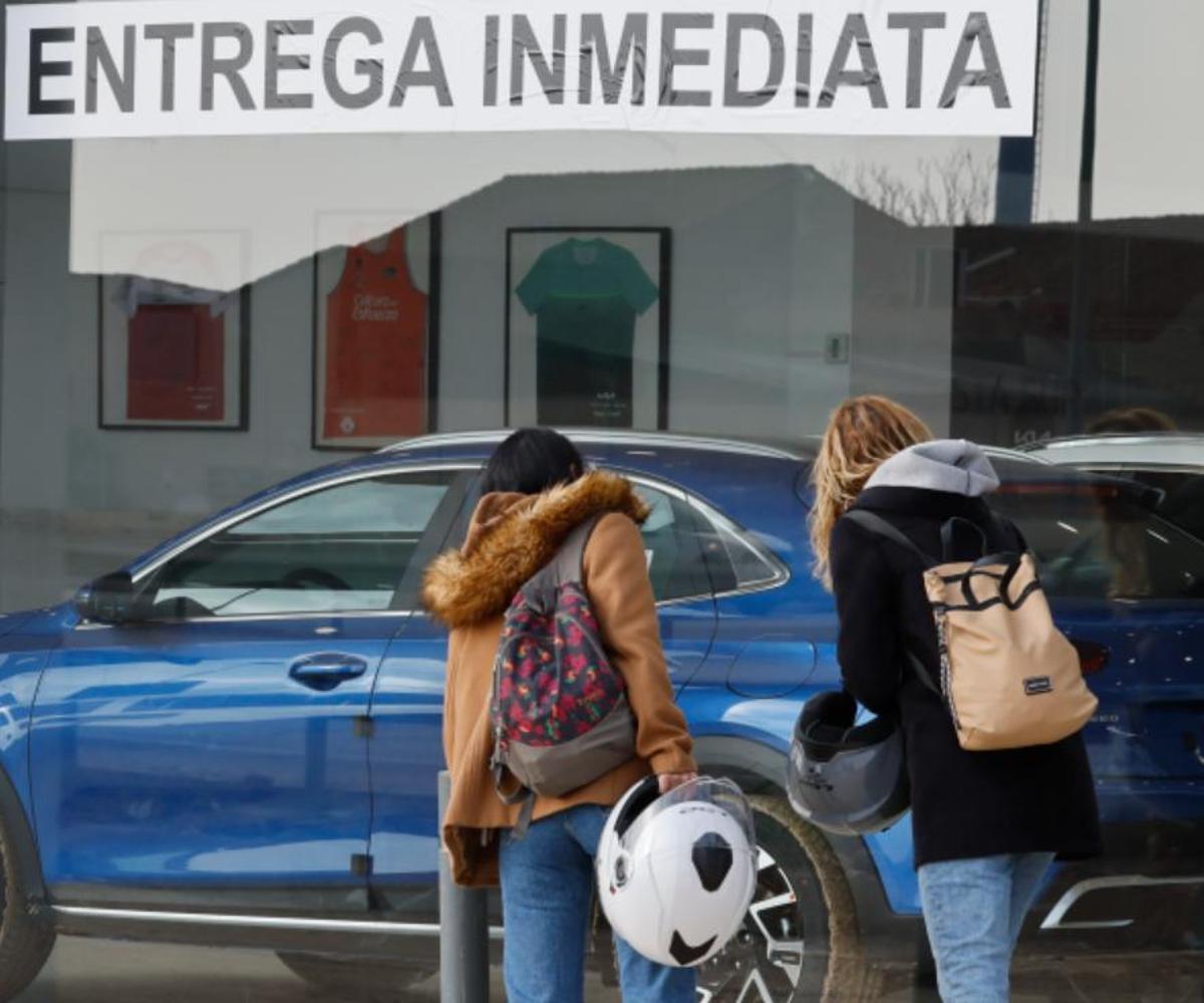 Dos mujeres miran coches en un concesionario.