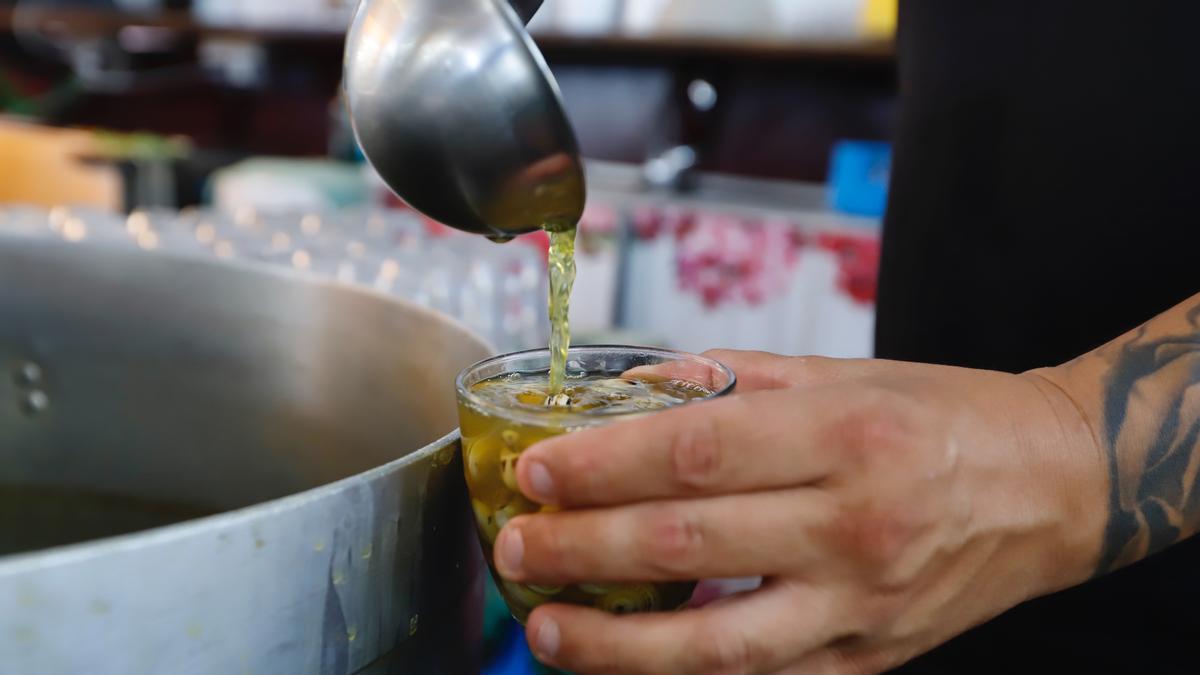 Un camarero sirve un vaso de caracoles en un puesto en Córdoba.