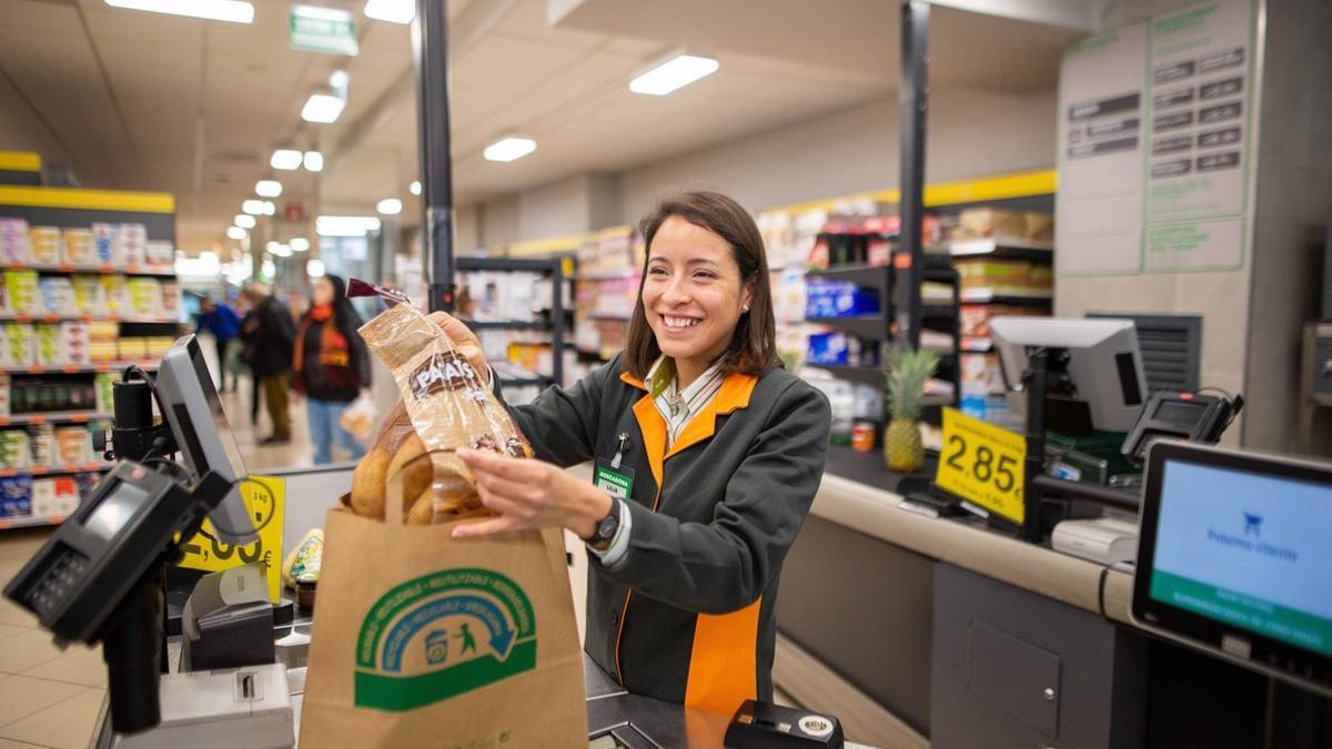 Una cajera de Mercadona deposita la compra en una bolsa de papel