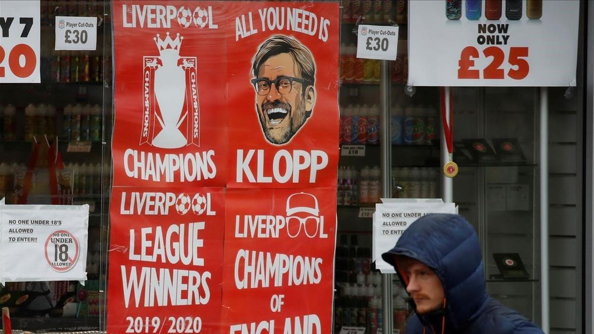 Un hombre pasa ante pancartas del Liverpool como campeón de la Premier.