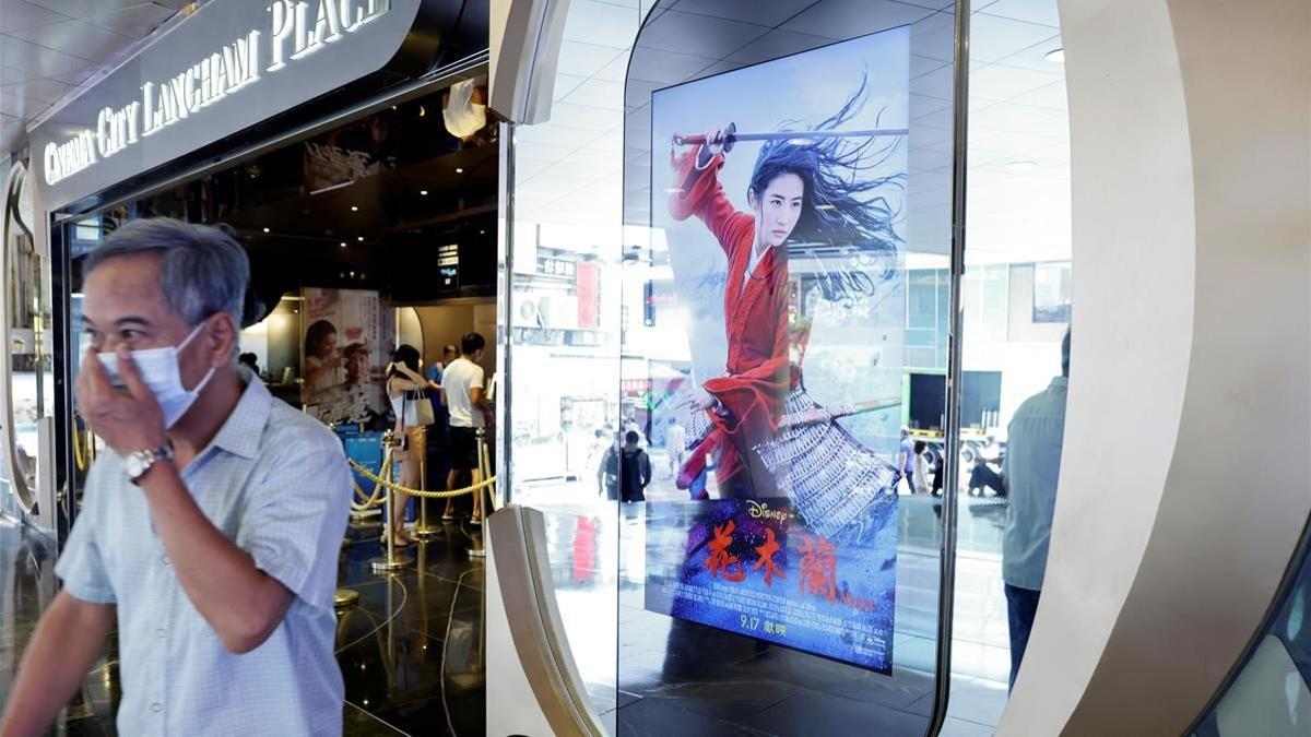 Un hombre con mascarilla pasa junto a un anuncio de 'Mulán' ante un cine de Hong Kong, la pasada semana.