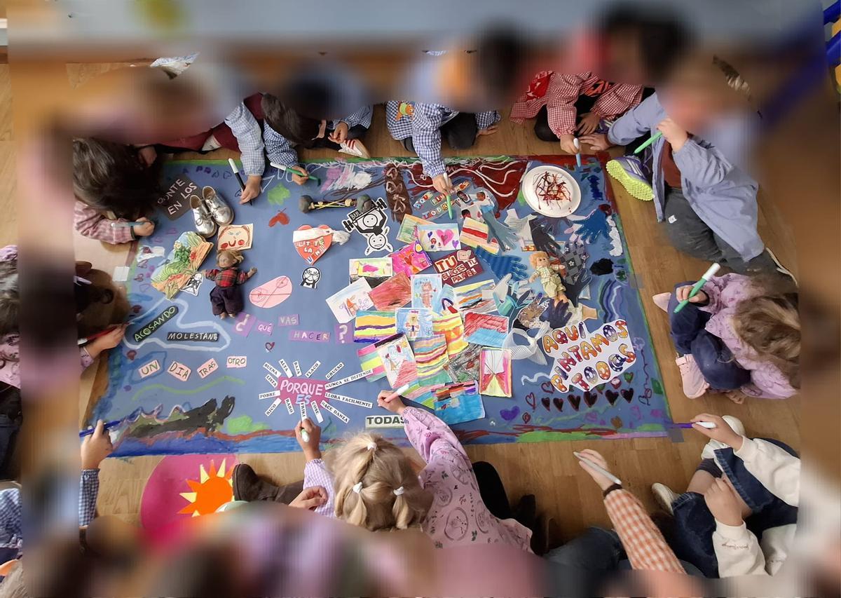 Imagen de la obra que ganó el certamen «Pinta contra el bullying», en la que varios pequeños aparecen en torno al trabajo y que ha sido difuminada en algunas zonas para proteger los rostros. | C. B. G.