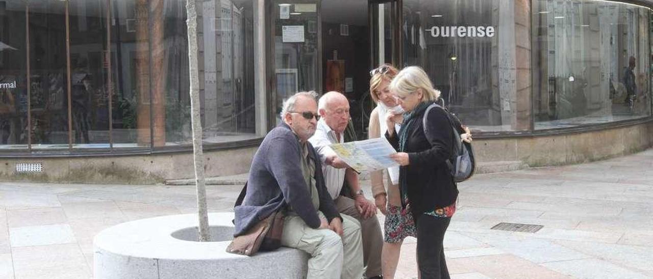 Visitantes consultan un folleto frente a la Oficina de Turismo de Ourense. // Iñaki Osorio