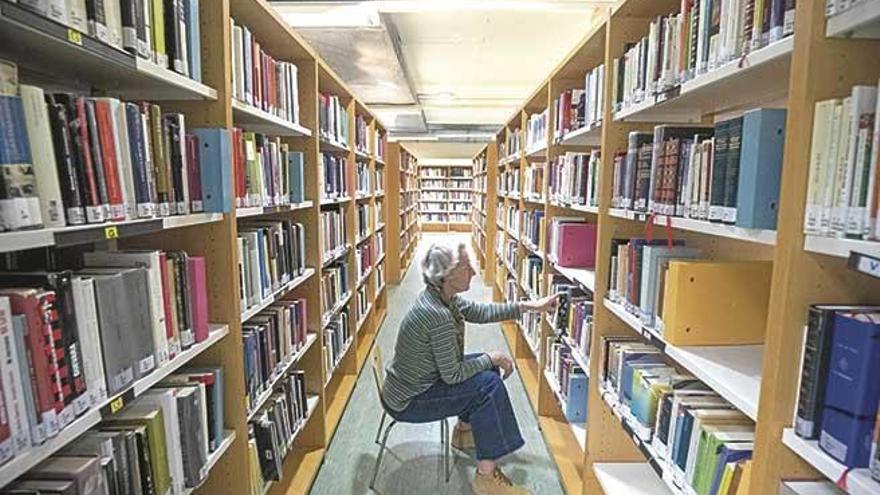 Una usuaria de la biblioteca Can Sales busca un libro entre sus estanterÃ­as.