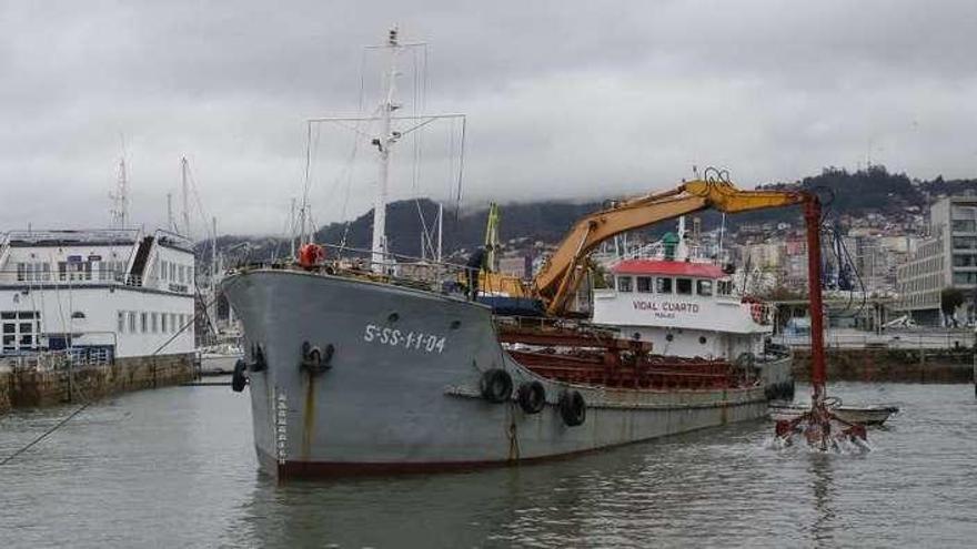 Un barco realiza las labores de dragado en la dársena de As Avenidas contratadas por el Puerto. // R. Grobas