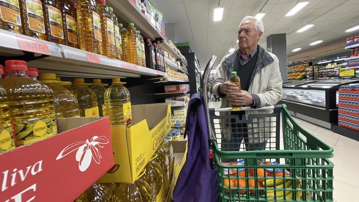 Un hombre mira el precio del aceite en un supermercado.