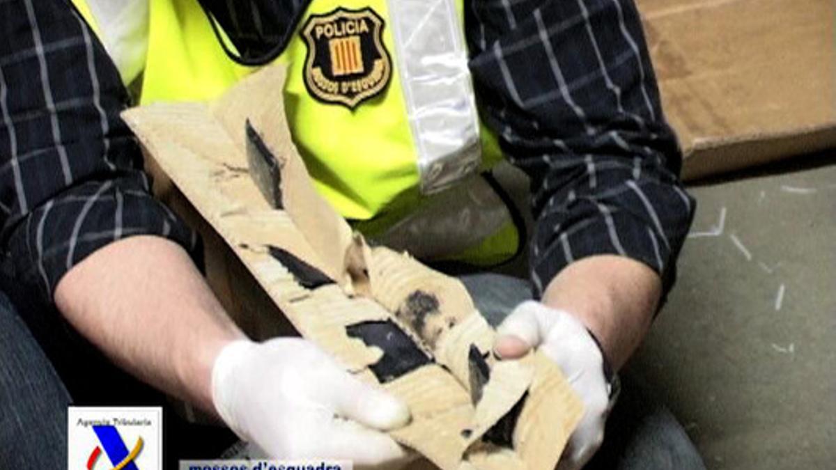 Un agente de los Mossos muestra los pliegues de la caja de cartón donde estaba oculta la heroína.