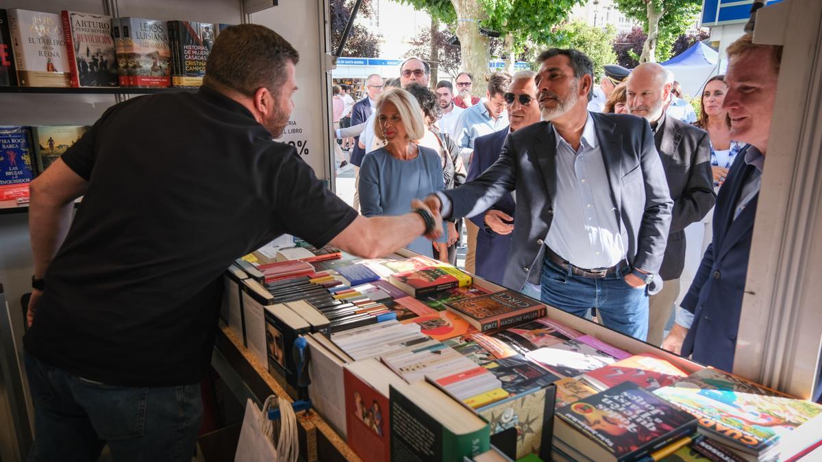 El escritor y pregonero de la Feria del Libro de Badajoz, Víctor del Árbol, saluda a uno de los expositores, junto al alcalde y la concejala de Cultura.