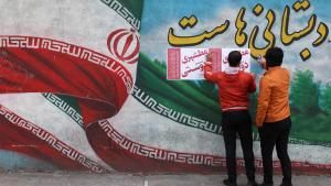 Hombres iraníes colocando carteles de campaña durante el último día de campaña electoral en Teherán.
