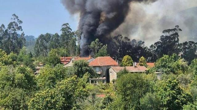 El humo del incendio en las proximidades de unas casas.