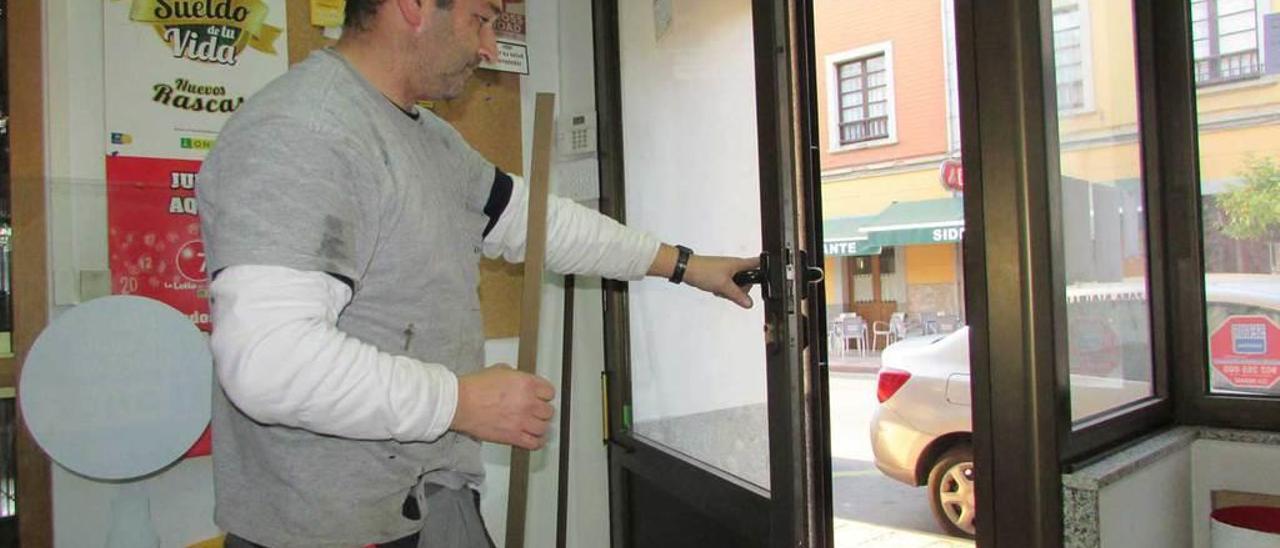 Un operario, colocando un cristal de seguridad en el estanco ayer.