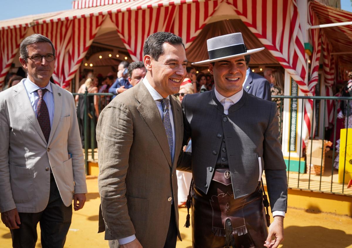 El presidente de la Junta de Andalucía, Juanma Moreno (c), junto al consejero de Industria, Energía y Minas, Jorge Paradela (i), pasean por la Feria de Abril.