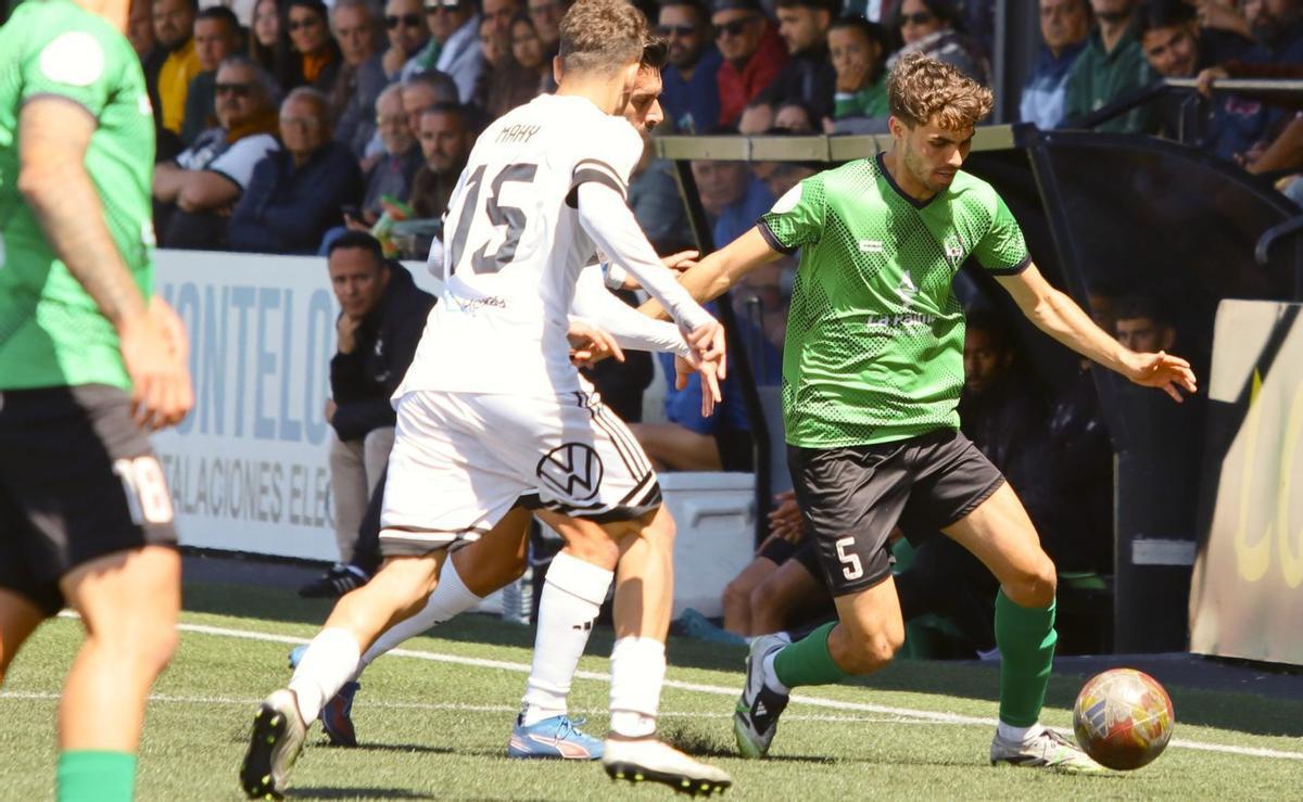 Javi Mayor conduce el balón ante la presencia de Mahy. |