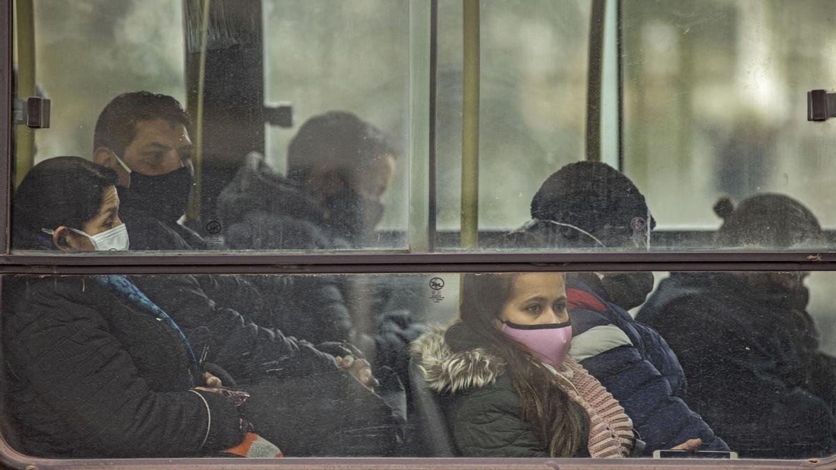 Viajeros con mascarilla en un autobús.