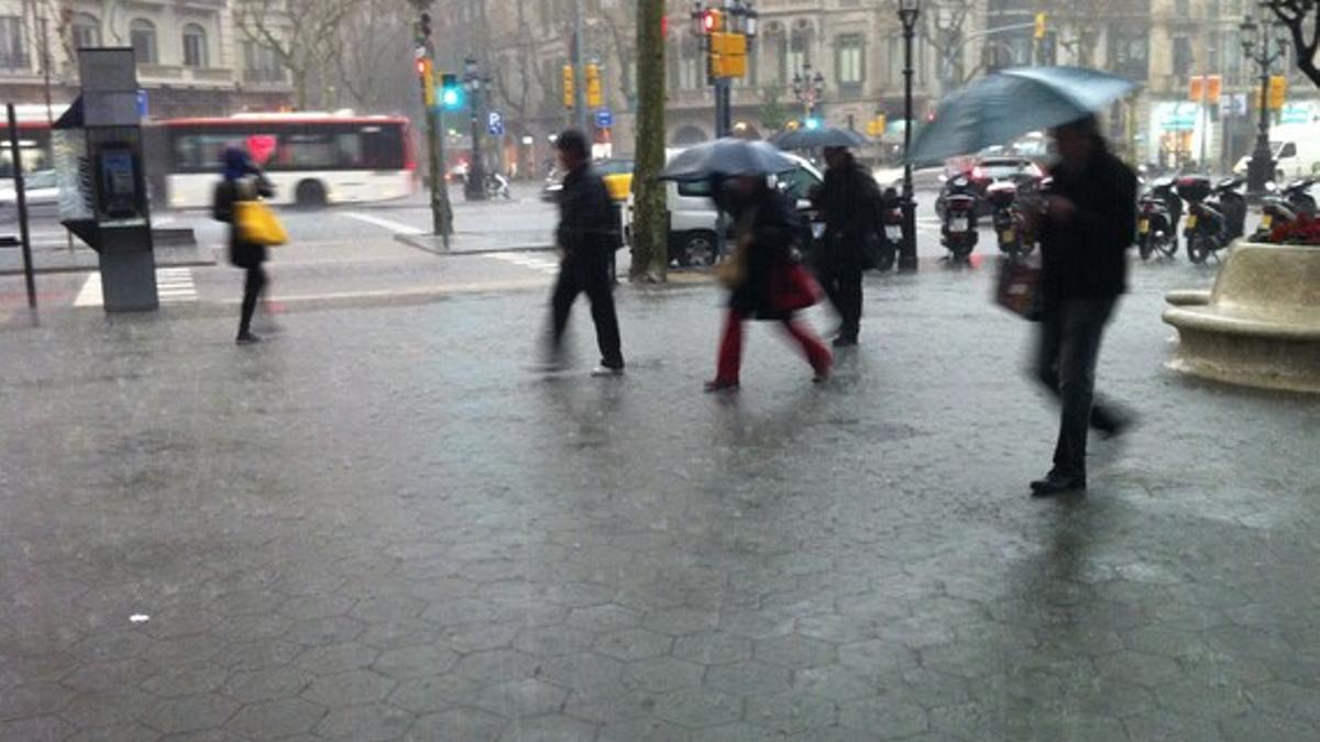 Transeúntes refugiándose de la lluvia en paseo de Gràcia.