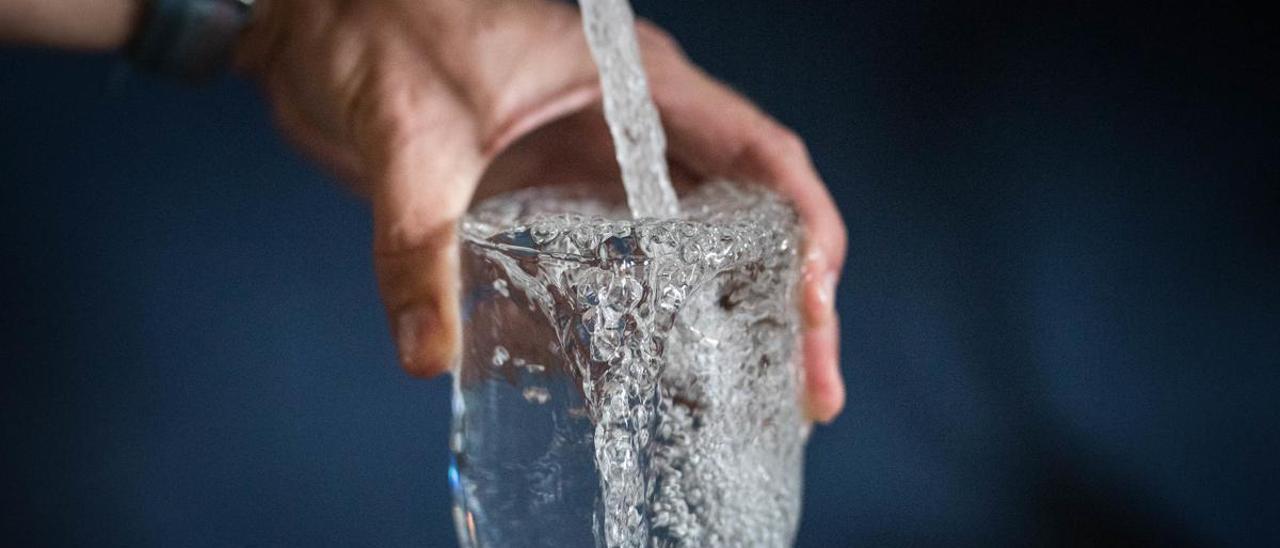 Una persona llena un vaso con agua del grifo.