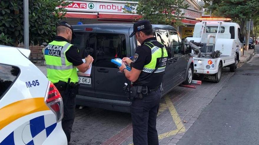 Dos agentes levantan acta a un vehículo inmovilizado por prestar servicios de transporte de personas sin la licencia.