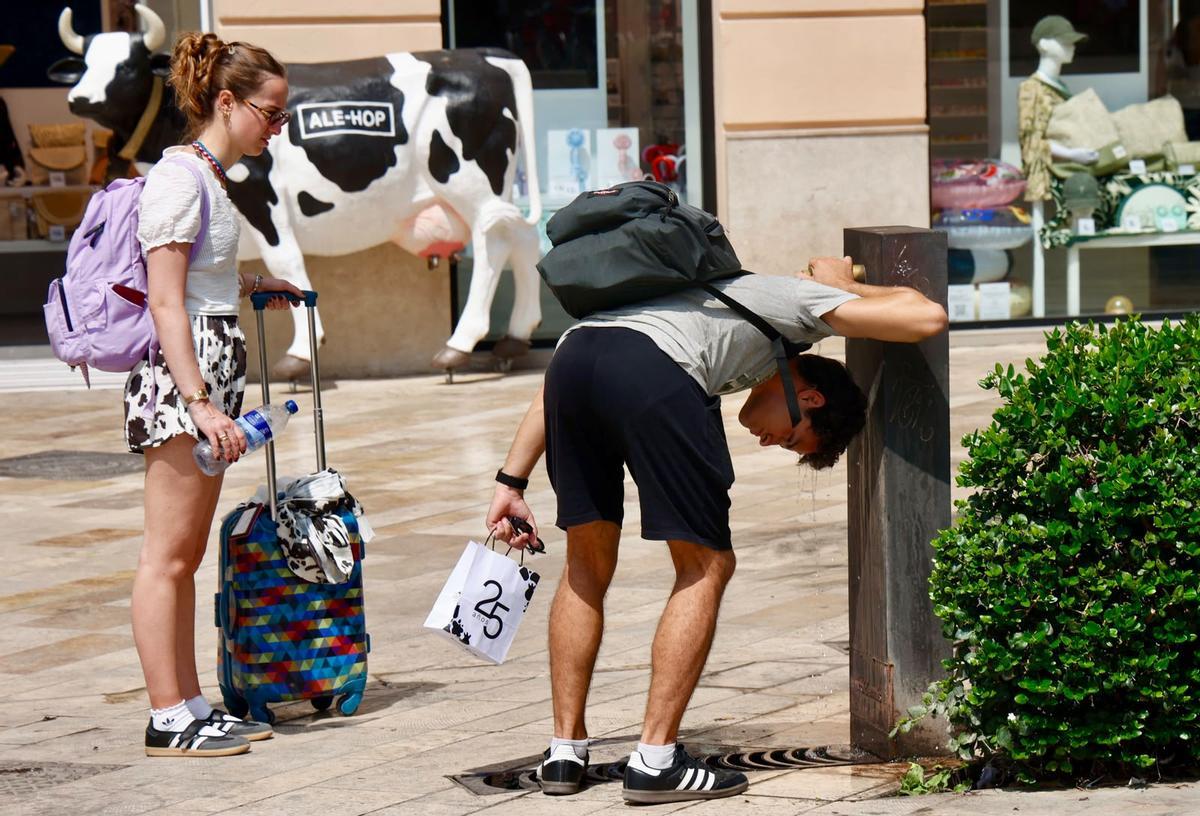 Un joven se refresca en una fuente en València, este uno de agosto