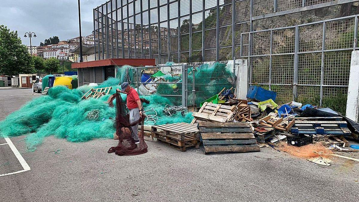 Un hombre manipula redes en una zona del puerto donde se acumula basura desde hace meses.