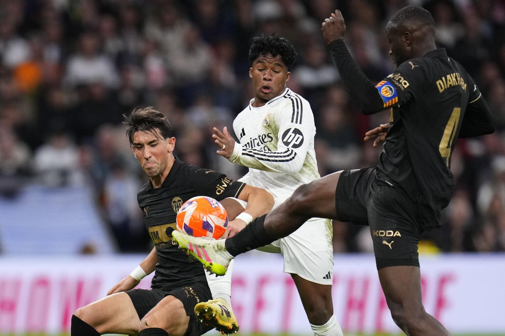Real Madrid's Endrick, center, Valencia's Jesus Vazquez, left, and Mouctar Diakhaby battle for the ball during a Spanish La Liga soccer match between Real Madrid and Valencia at the Santiago Bernabeu stadium in Madrid, Spain, Saturday, April 5, 2025. (AP Photo/Manu Fernandez). EDITORIAL USE ONLY/ONLY ITALY AND SPAIN