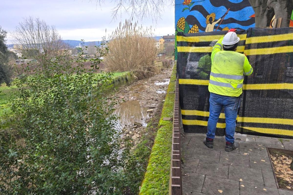 Un operari instal·la unes tanques per les obres de reparació del mur de la séquia Monar de Girona