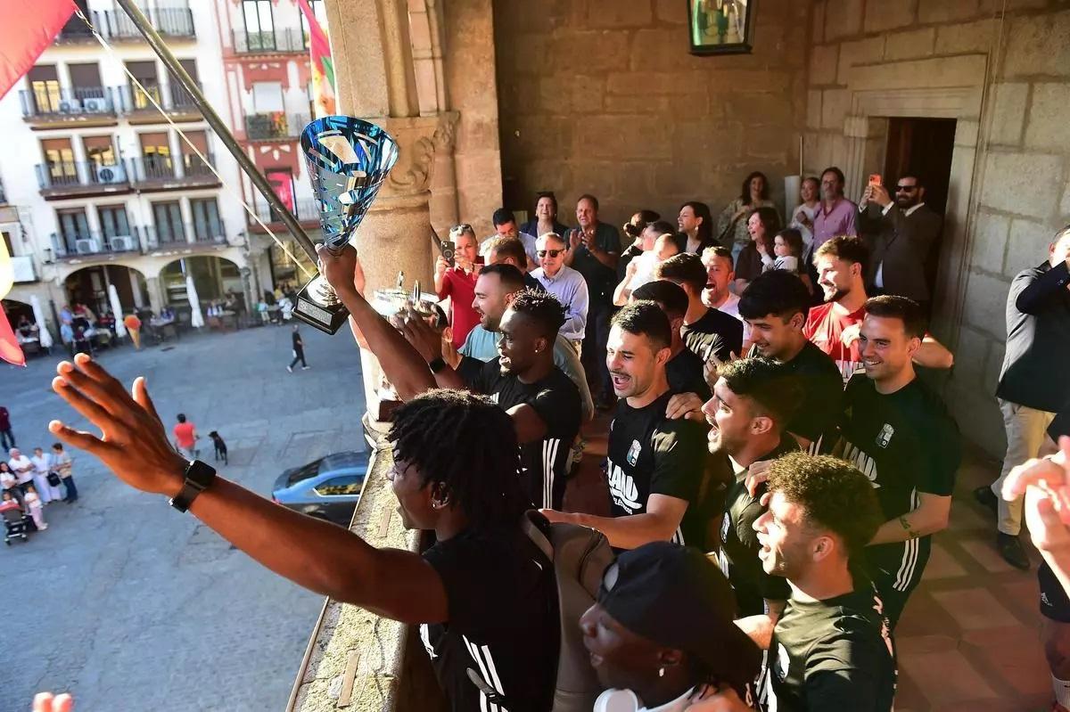 Chinaza Marvellous, en primer término, festeja con sus compañeros del Plasencia el ascenso a Tercera desde el balcón del ayuntamiento.