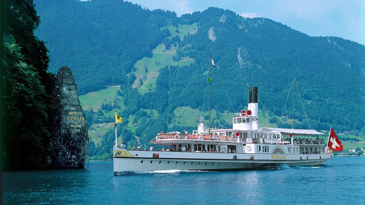 Uno de los barcos históricos navega por el Lago de los Cuatro Cantones, etapa lacustre del Gotthard Panorama Express antes de continuar el recorrido en tren hacia el sur del país