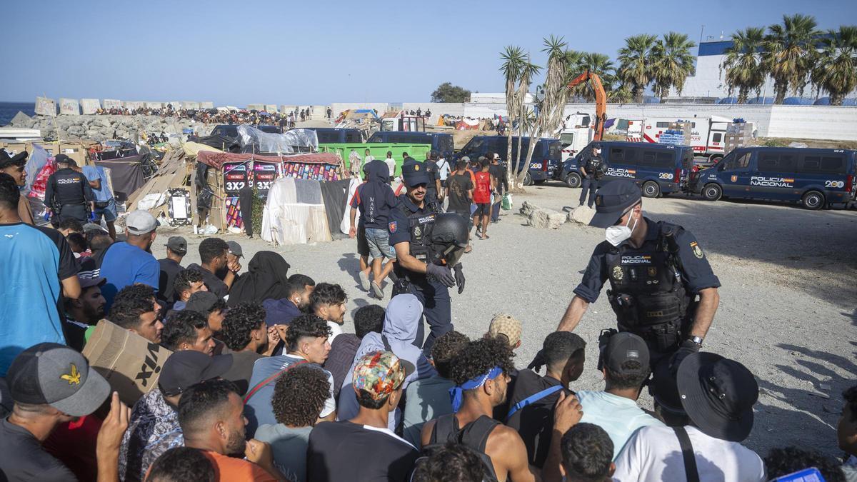 Varios agentes de Policía Nacional controlan a los migrantes en la playa de Trampolín de Ceuta