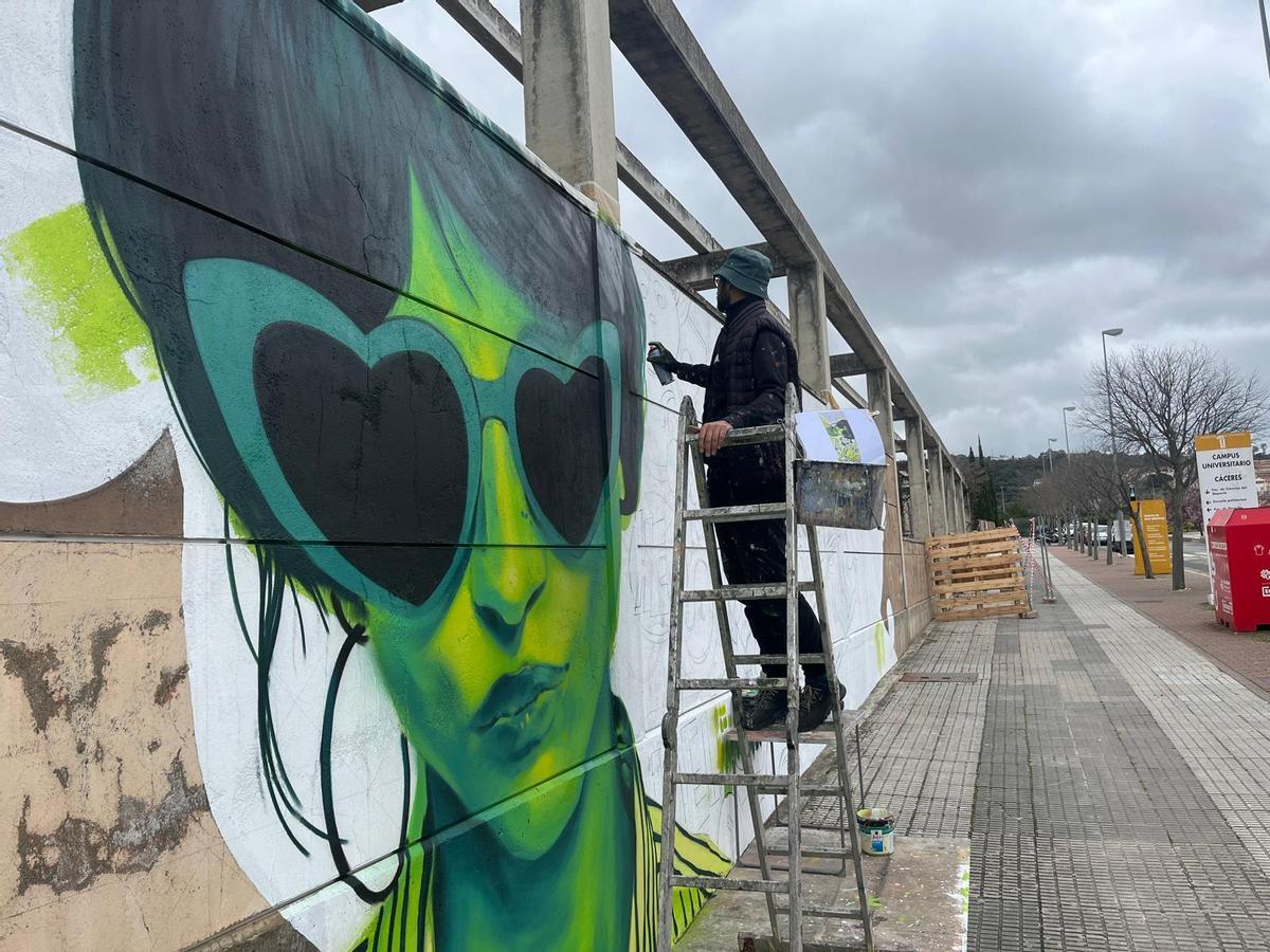 Sojo sigue pintando el nuevo mural bajo la lluvia.