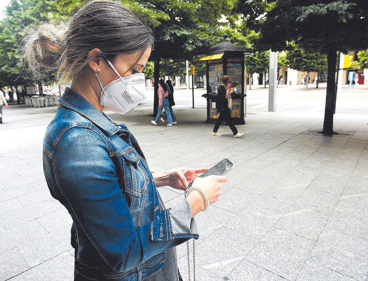 Una zaragozana mira atenta su móvil mientras camina por el paseo Independencia de Zaragoza