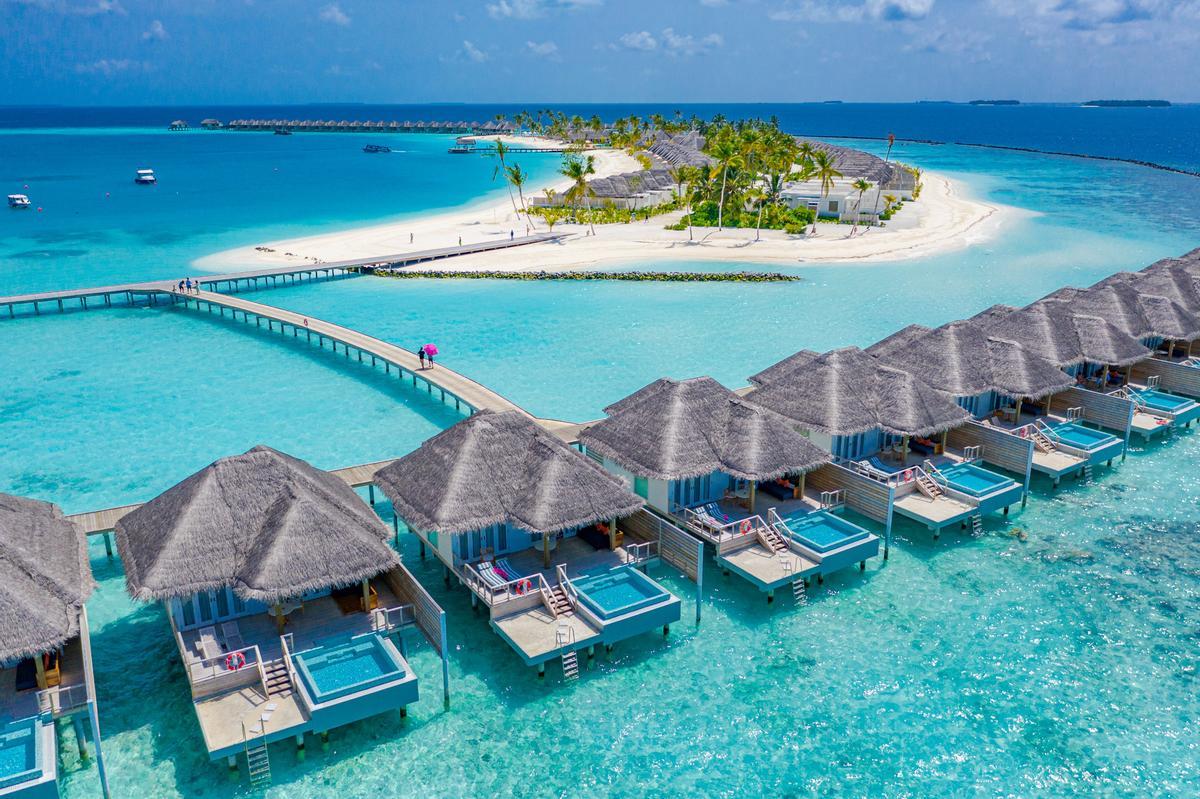 Vista aérea de la isla de Maldivas, complejo de villas de lujo con agua y muelle de madera.