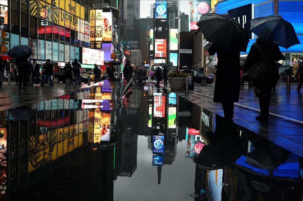 Peatones de Times Square reflejados en la lluvia de la ciudad que nunca duerme, New York