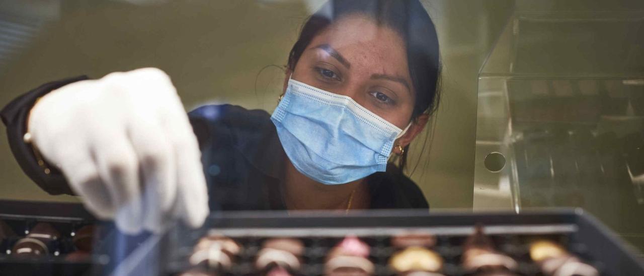 Una empleada de un establecimiento comercial de la capital tinerfeña realiza su trabajo protegida con una mascarilla.