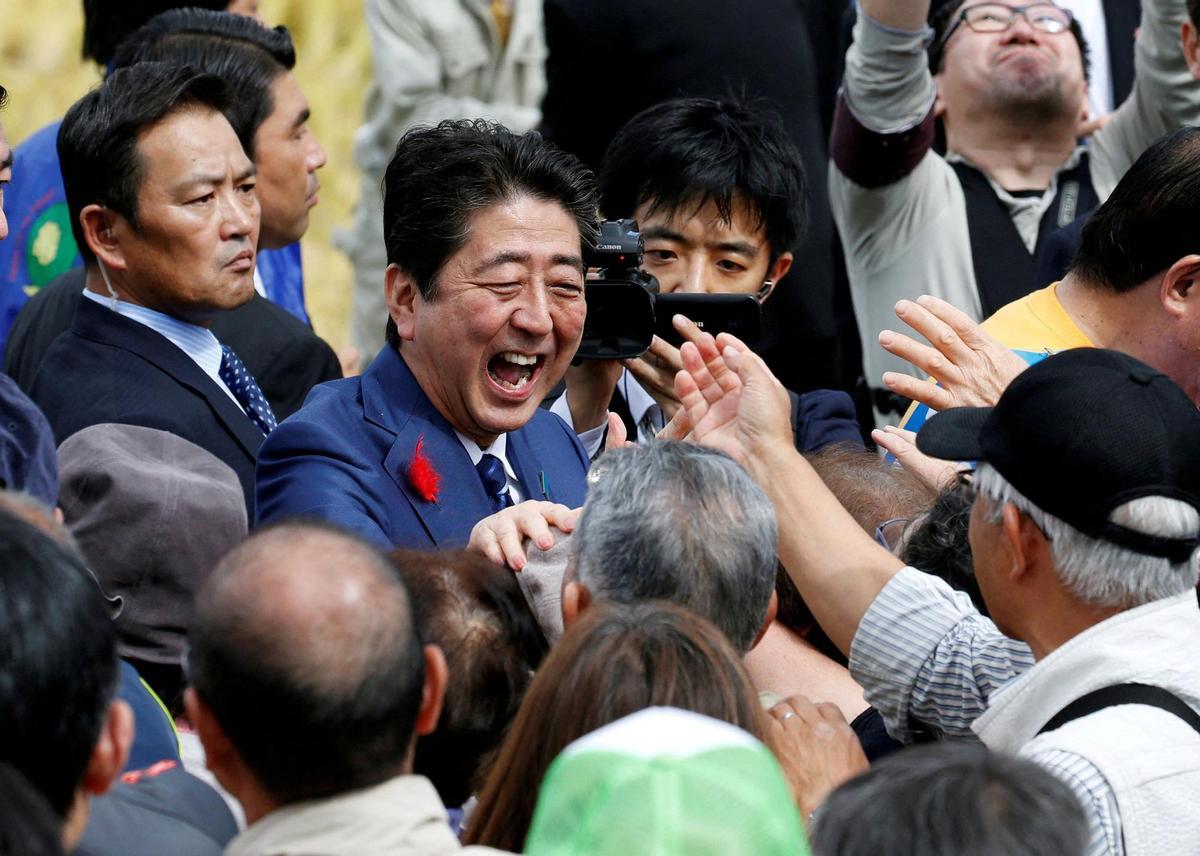 FILE PHOTO: Japans Prime Minister Shinzo Abe, who is also ruling Liberal Democratic Party leader, shakes hands with his supporters after an election campaign rally in Fukushima