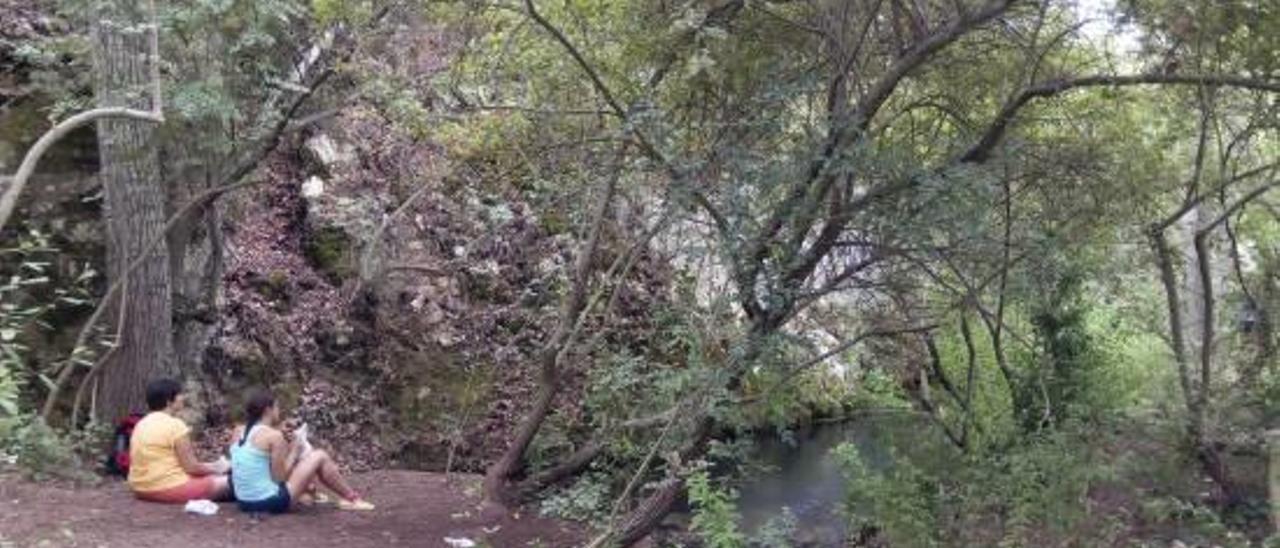 Dos excursionistas descansan en el nacimiento del río Vinalopó, en el parque de la Mariola.