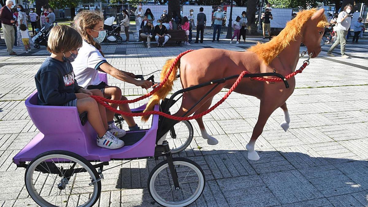 Dos niños ayer, en el caballo restaurado, ante las familias que hicieron cola para subir a él.  | // CARLOS PARDELLAS