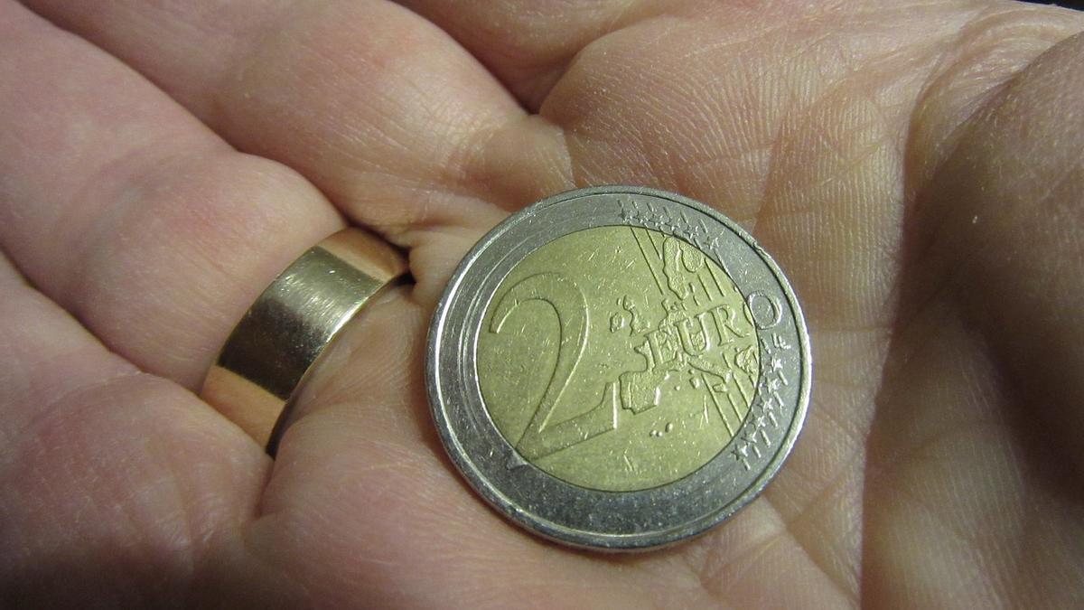 Una persona sostiene en la palma de la mano una moneda de 2 euros