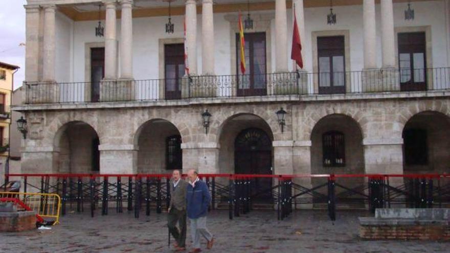 Dos personas pasan junto a la fachada principal del Consistorio toresano.