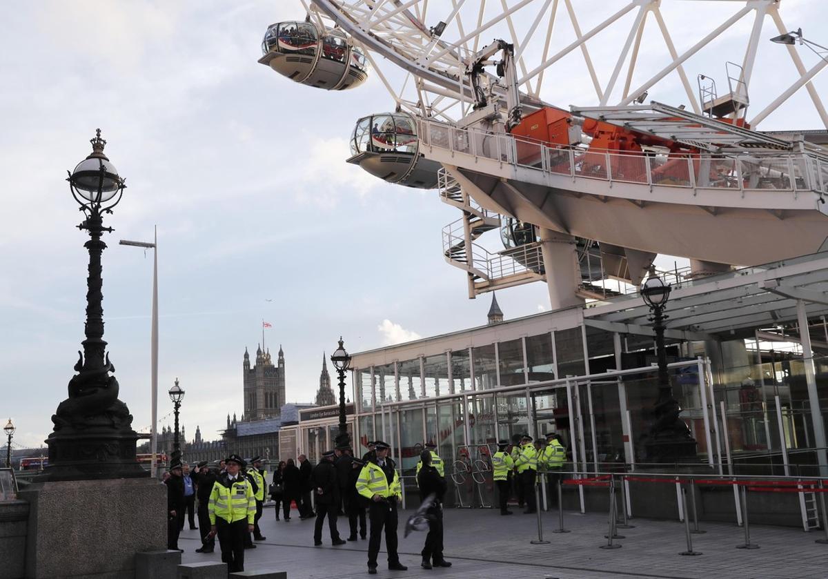 Police officers stand at the exit as people are seen inside the pods on the London Eye after it was stopped following an attack on Westminster Bridge in London, Britain March 22, 2017.     REUTERS/Eddie Keogh