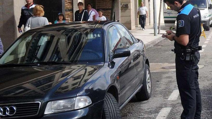 Un agente formula una denuncia a un coche estacionado en zona no permitida. // R. Vázquez